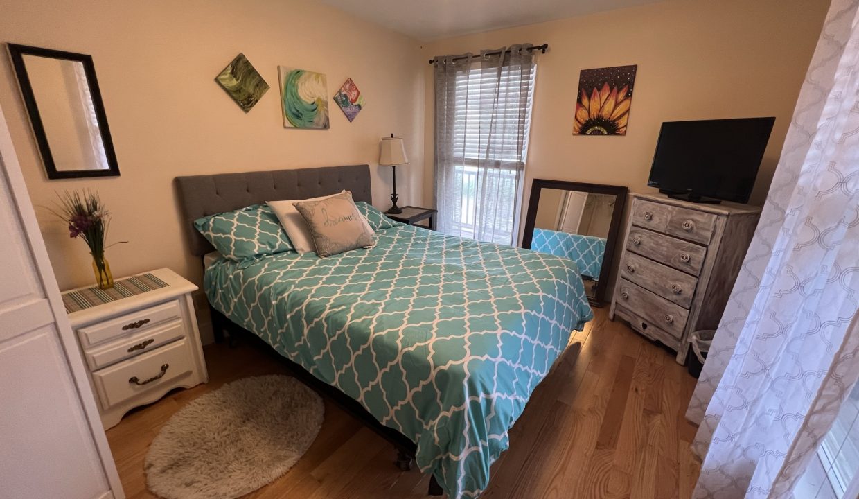 a bed room with a neatly made bed and a flat screen tv.