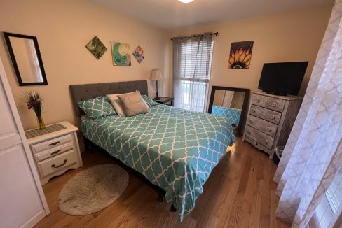 a bed room with a neatly made bed and a flat screen tv.