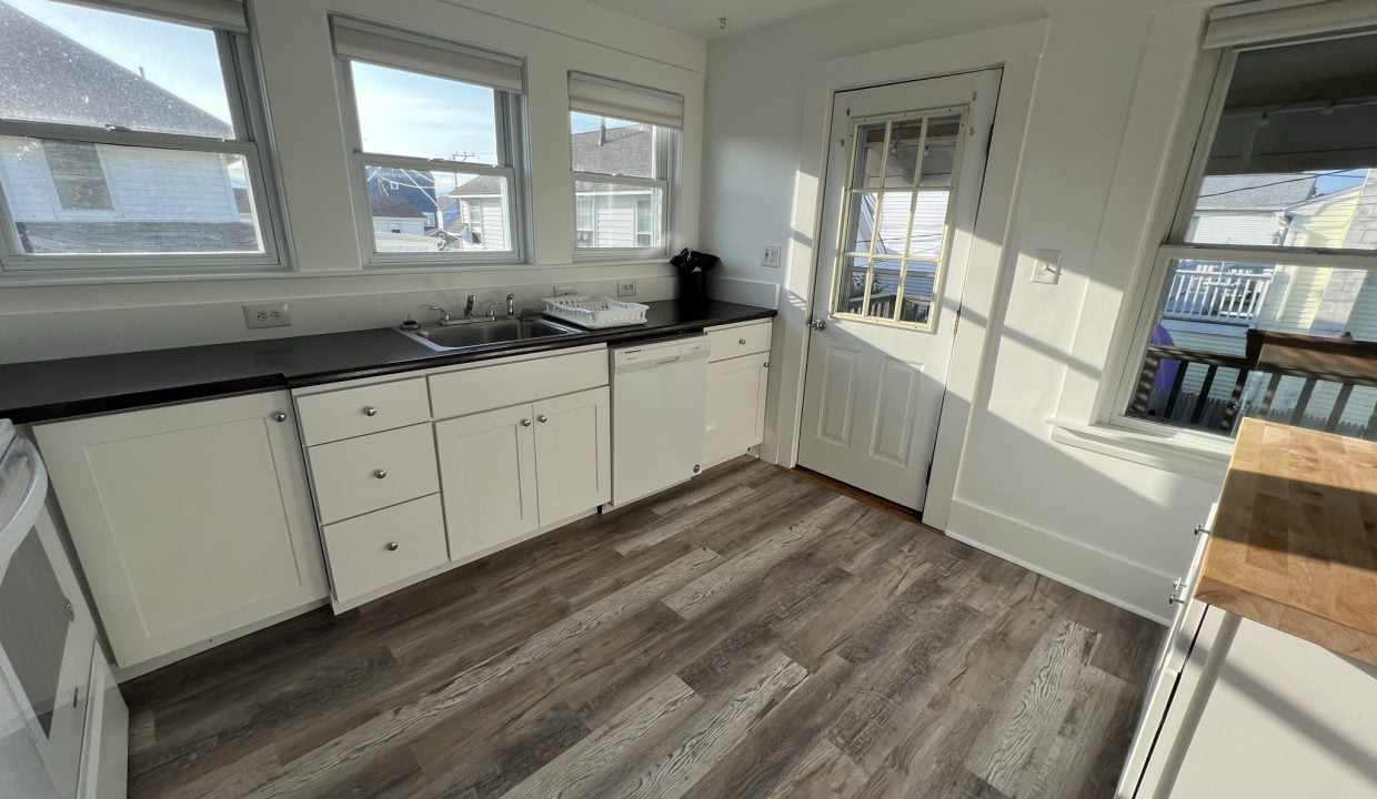 a kitchen with white cabinets and black counter tops.