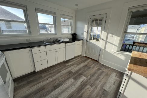 a kitchen with white cabinets and black counter tops.