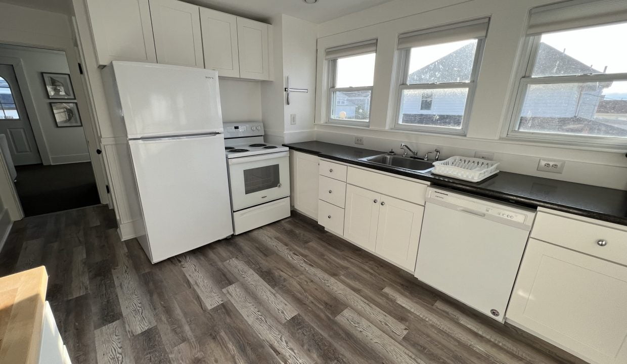 a kitchen with white cabinets and black counter tops.