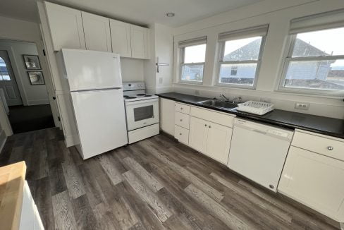 a kitchen with white cabinets and black counter tops.