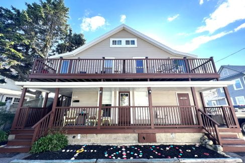 a two story house with a deck and stairs.