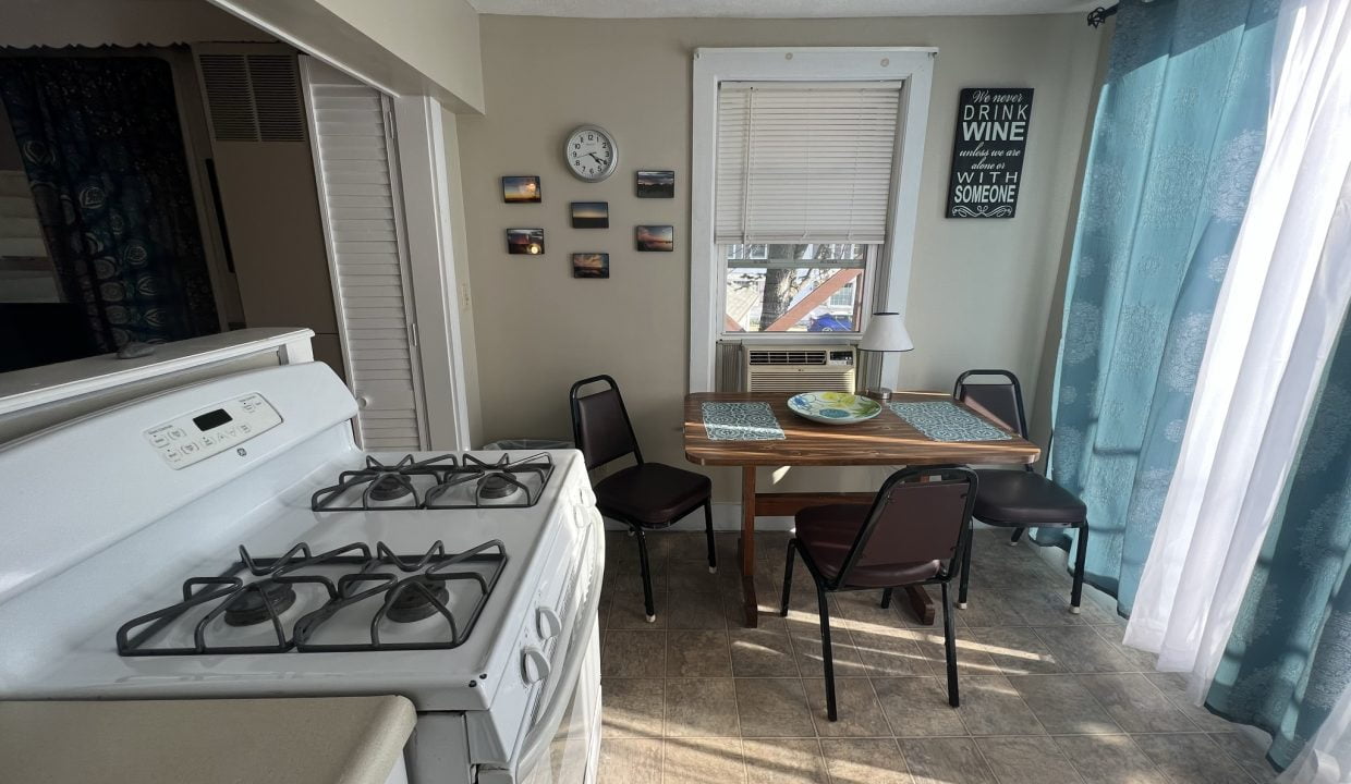 a kitchen with a stove, table, and chairs.