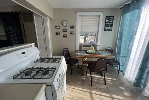 a kitchen with a stove, table, and chairs.