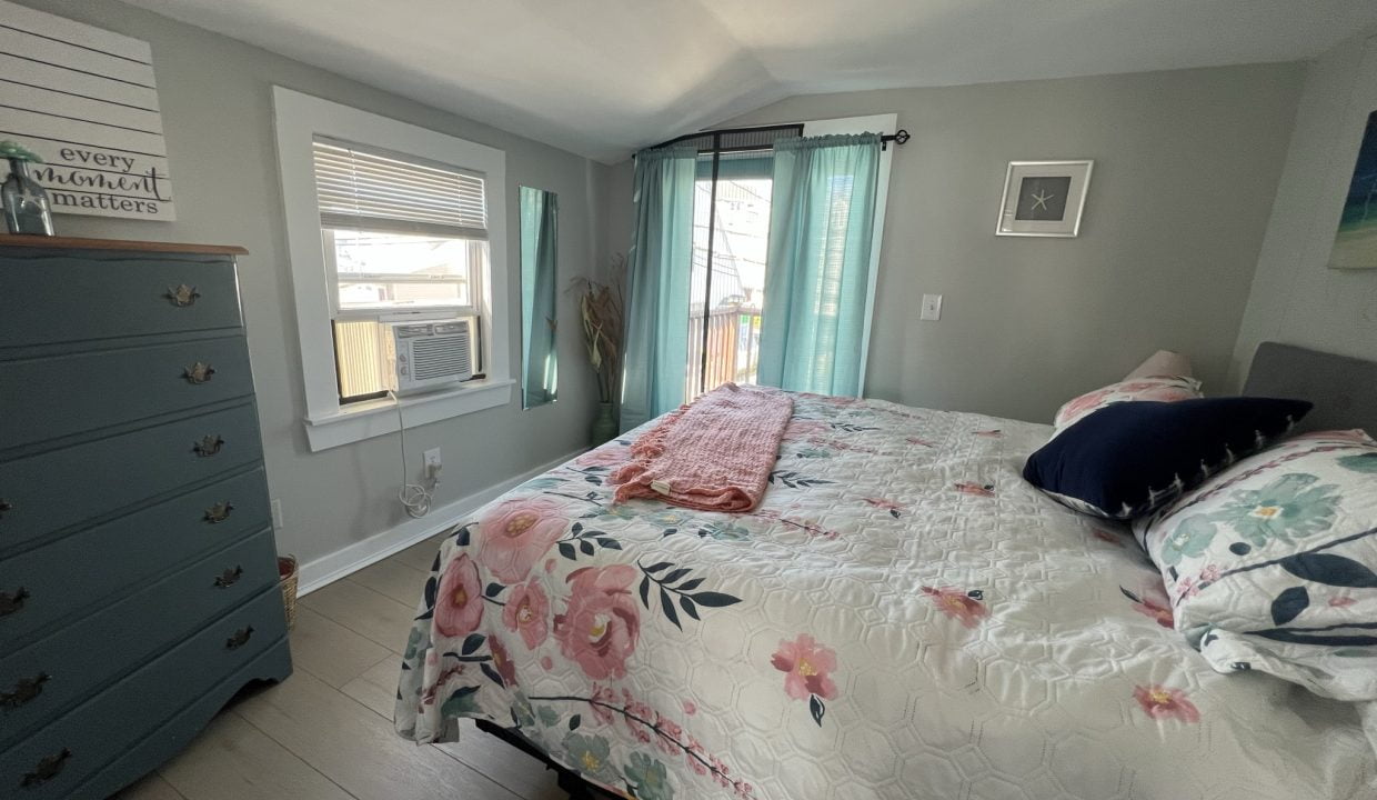 a bedroom with a bed, dresser, and window.