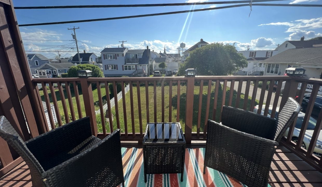 two wicker chairs sitting on a wooden deck.