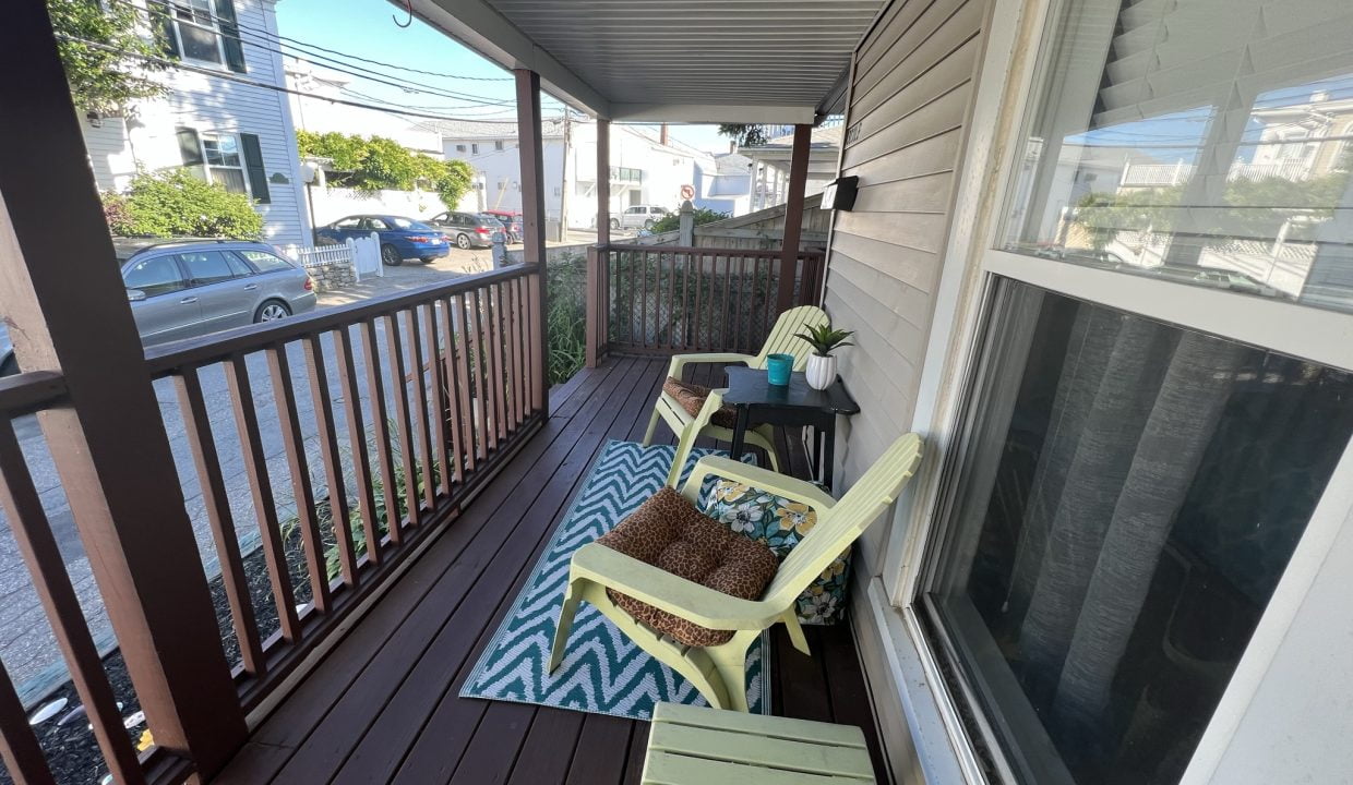 a porch with two chairs and a rug on it.