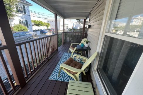 a porch with two chairs and a rug on it.