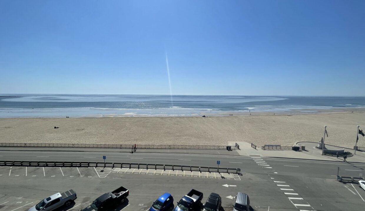 a parking lot next to a beach with cars parked in it.