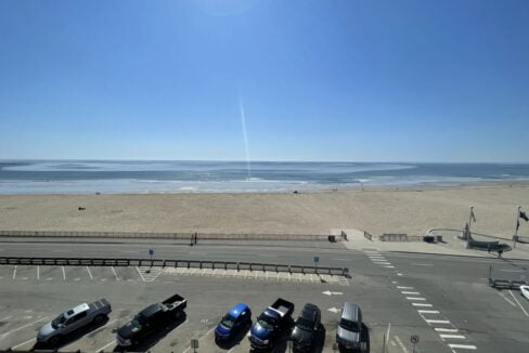 a parking lot next to a beach with cars parked in it.