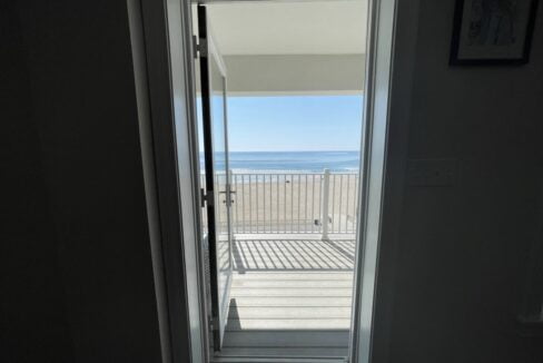 an open door leading to a balcony with a view of the ocean.