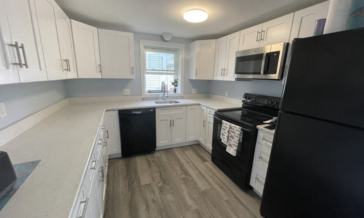 a kitchen with white cabinets and black appliances.