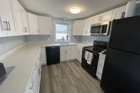 a kitchen with white cabinets and black appliances.