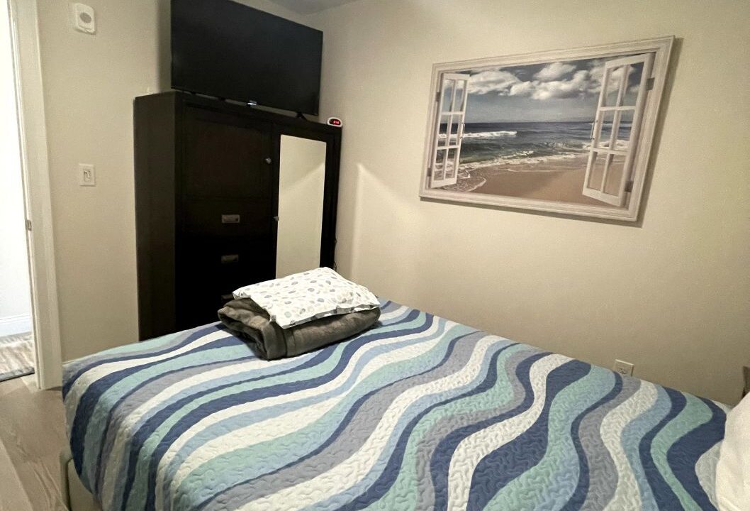 a bed room with a neatly made bed and a ceiling fan.