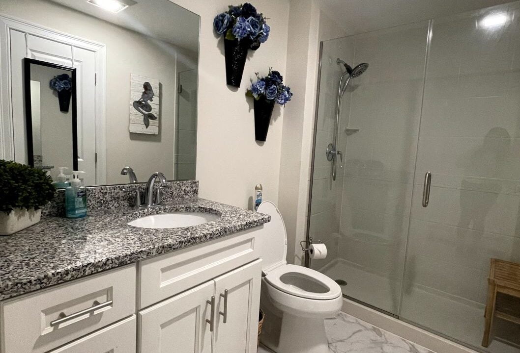a bathroom with a toilet, sink, and shower.
