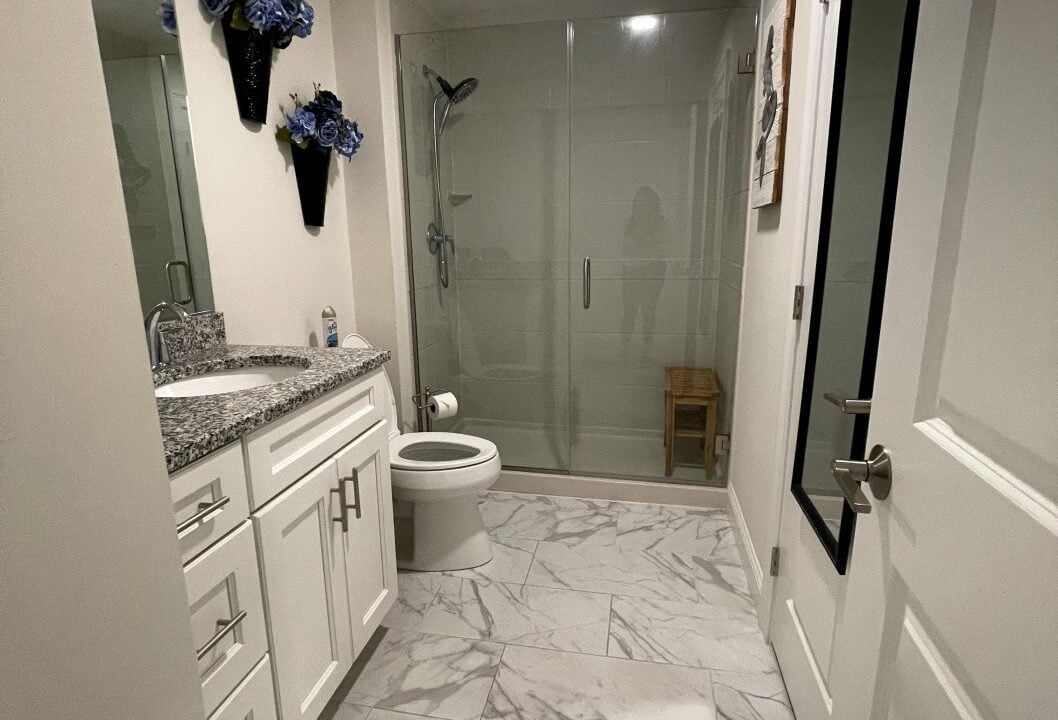 a bathroom with a toilet, sink, and shower.