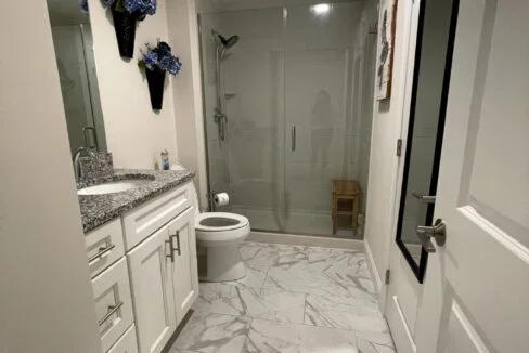 a bathroom with a toilet, sink, and shower.
