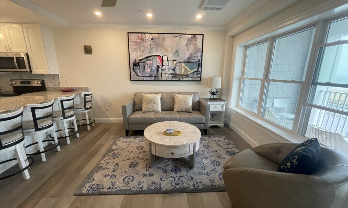 a living room filled with furniture next to a kitchen.