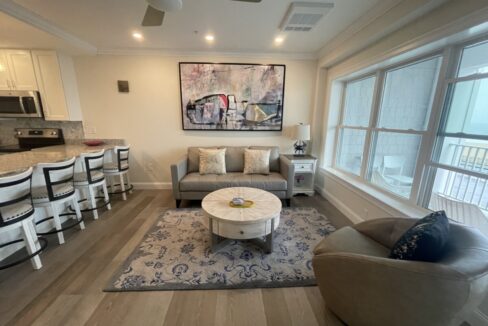 a living room filled with furniture next to a kitchen.