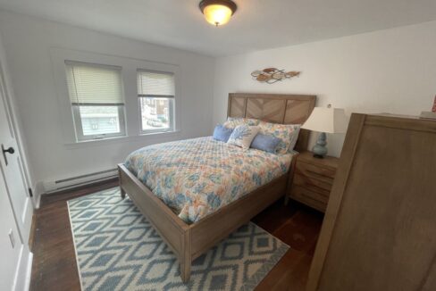 a bed room with a neatly made bed and a dresser.