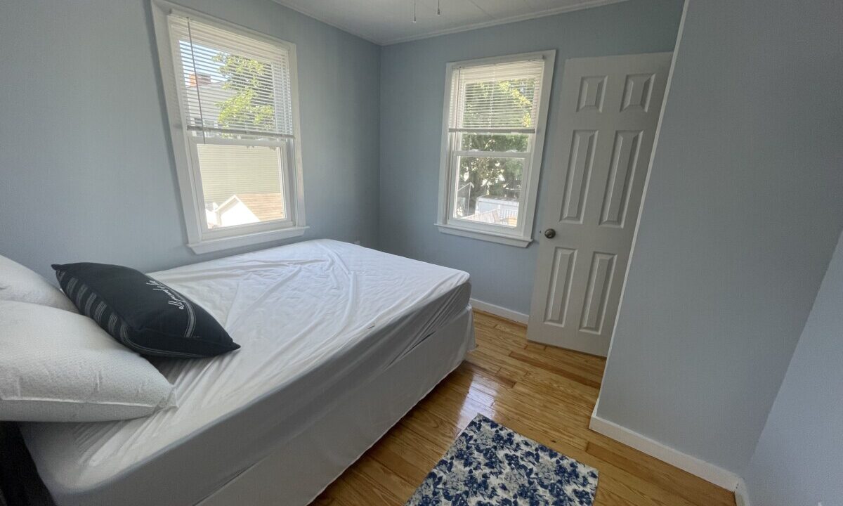 a bed sitting in a bedroom next to two windows.