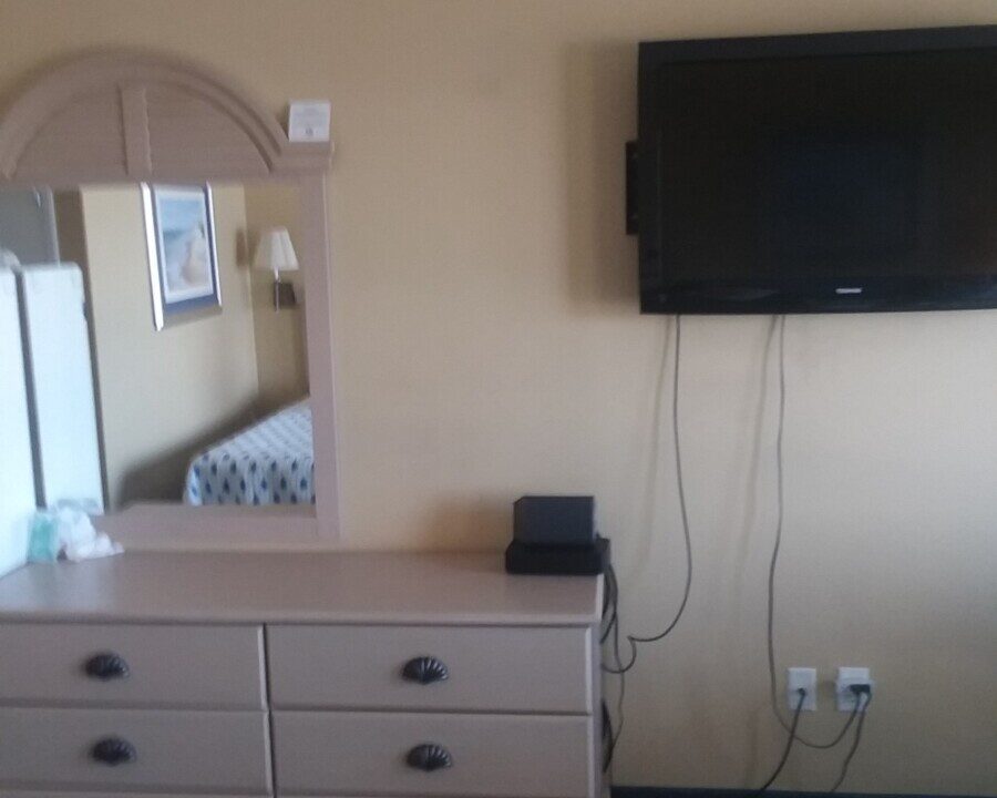 a bedroom with a dresser, mirror and television.