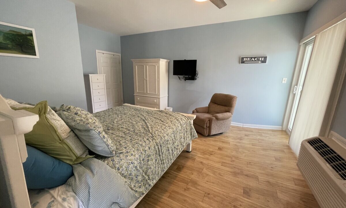 a bed room with a neatly made bed and a flat screen tv.