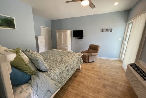 a bed room with a neatly made bed and a flat screen tv.