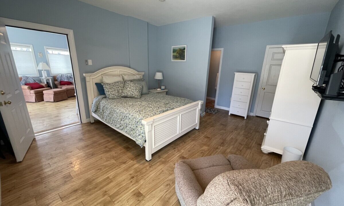 a bed room with a neatly made bed and a chair.