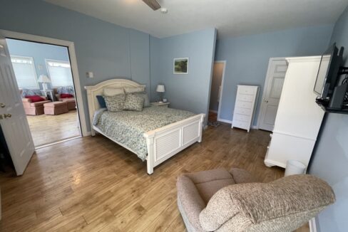 a bed room with a neatly made bed and a chair.