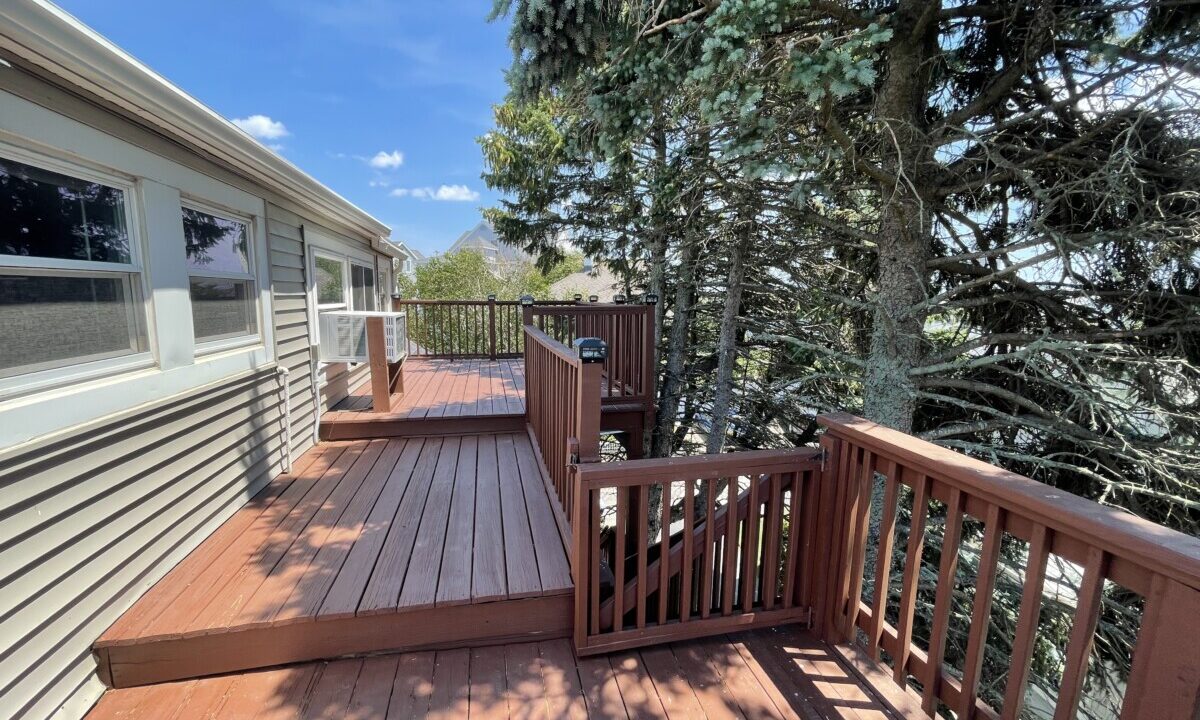 a wooden deck with railings and trees in the background.