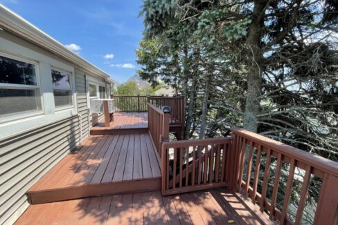a wooden deck with railings and trees in the background.