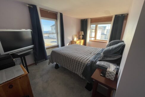 a bed room with a neatly made bed and a flat screen tv.