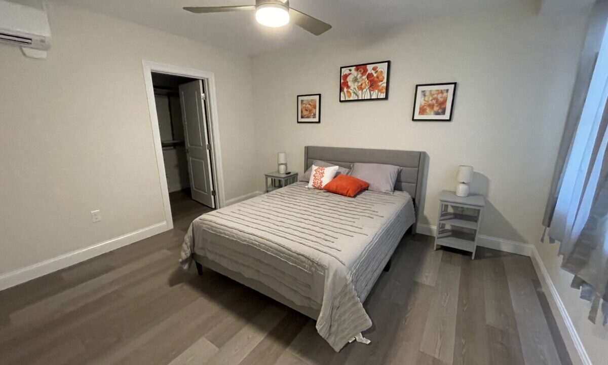 a bed room with a neatly made bed and a ceiling fan.