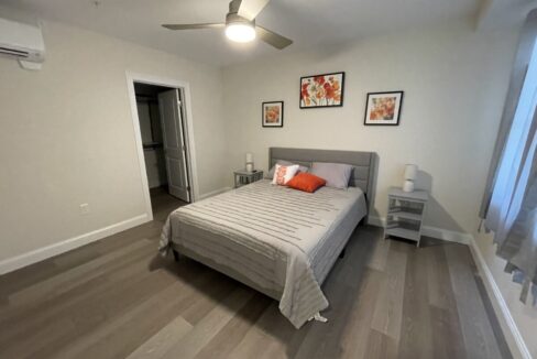 a bed room with a neatly made bed and a ceiling fan.