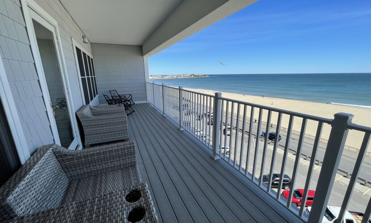 a balcony with wicker furniture and a view of the beach.