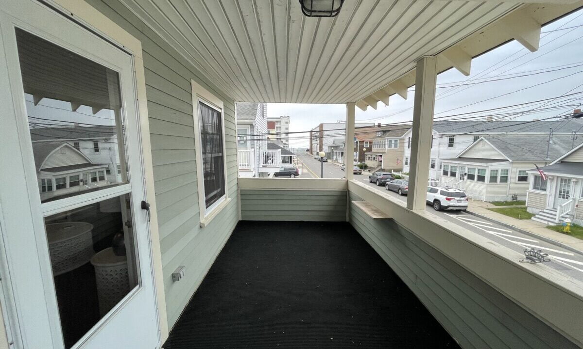 a porch with a black floor and white siding.