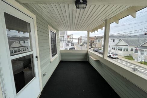 a porch with a black floor and white siding.