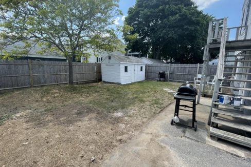 a back yard with a fence and a fire hydrant.