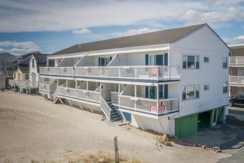 Beachfront multi-story residential building with balconies and ground-level parking.