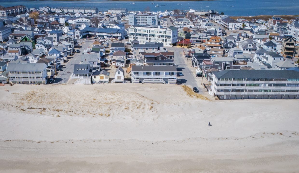 Aerial view of a coastal town with buildings adjacent to a sandy beach.