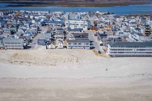 Aerial view of a coastal town with buildings adjacent to a sandy beach.