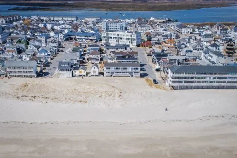 Aerial view of a coastal town with buildings adjacent to a sandy beach.