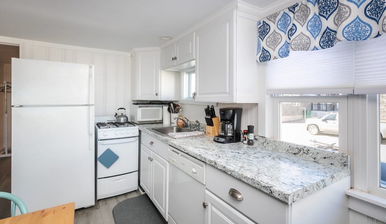 Modern kitchen interior with white appliances, granite countertops, and a blue patterned window treatment.