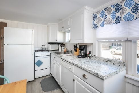 Modern kitchen interior with white appliances, granite countertops, and a blue patterned window treatment.