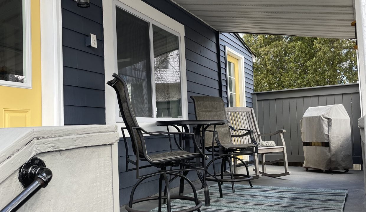 a porch with a table and chairs on it.