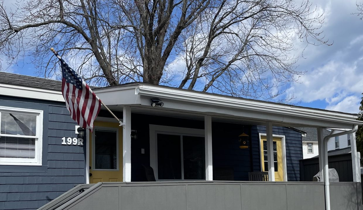 a blue house with a flag on the porch.