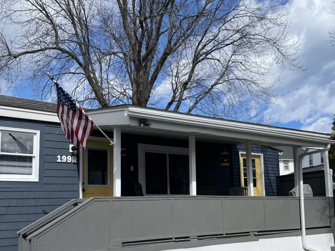 a blue house with a flag on the porch.