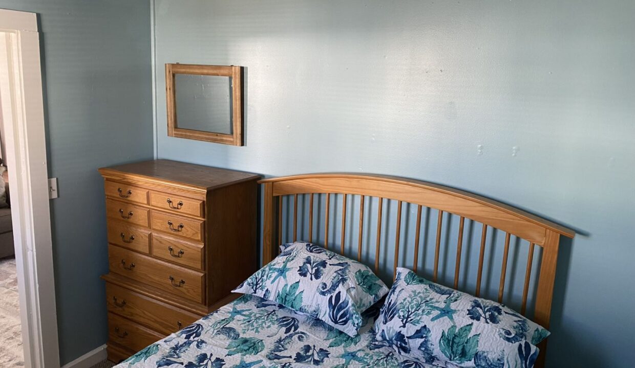 a bedroom with a bed, dresser and mirror.